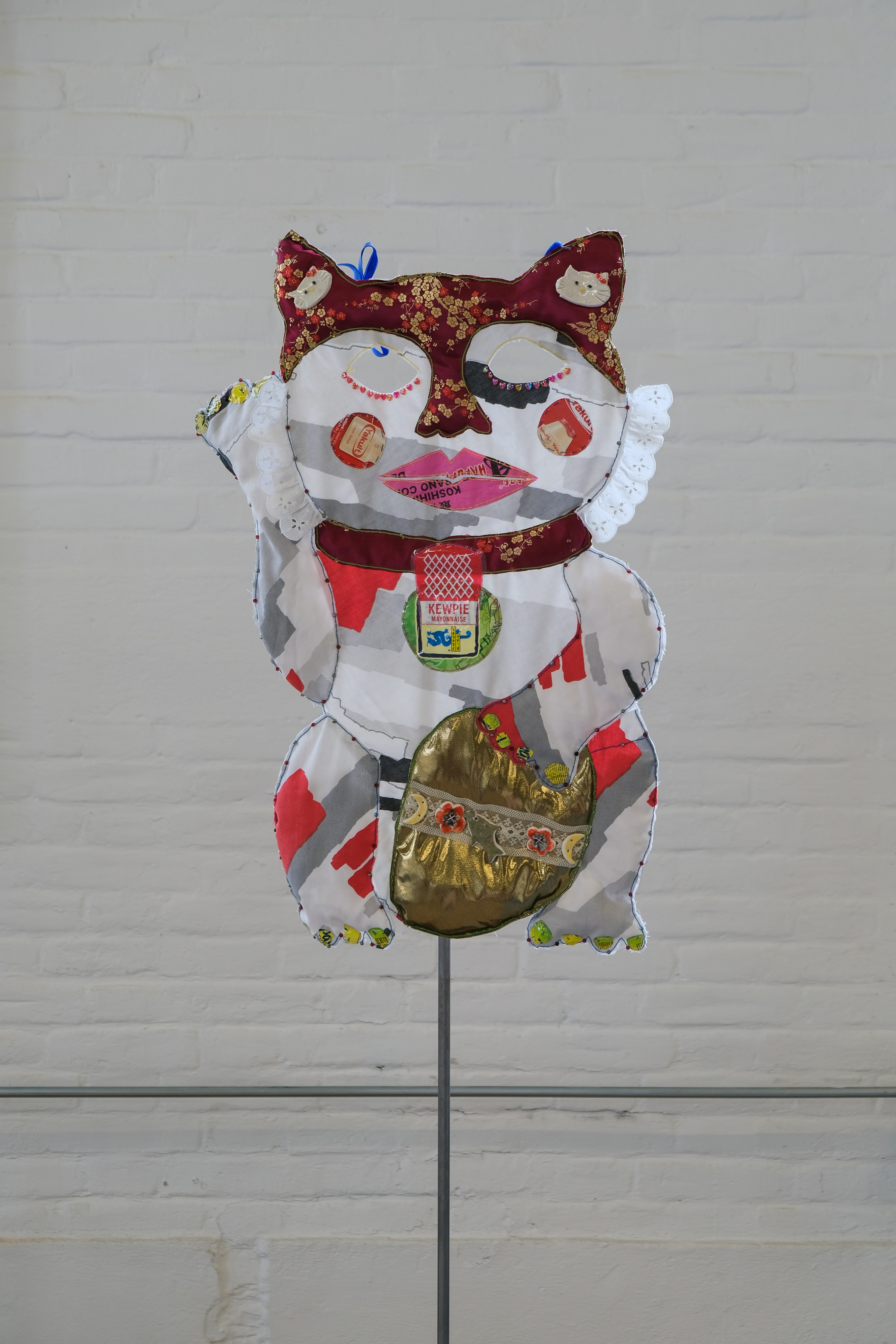 Asian Lucky Cat Mask constructed out of found textiles, ceramics, and packaging.